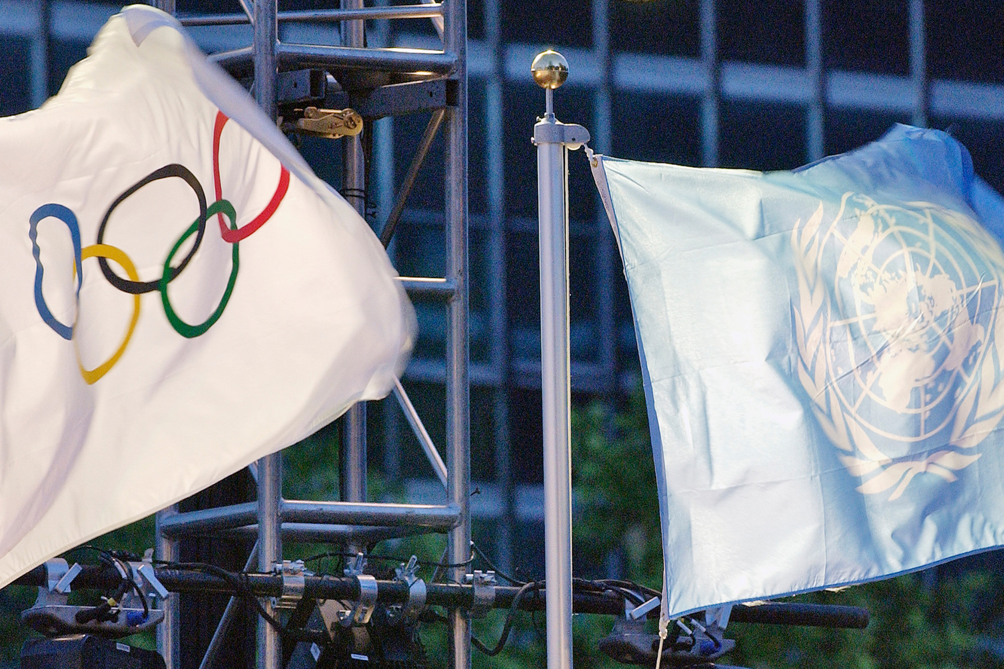 The United Nations and Olympic flags are raised in front of the United Nations Headquarters.