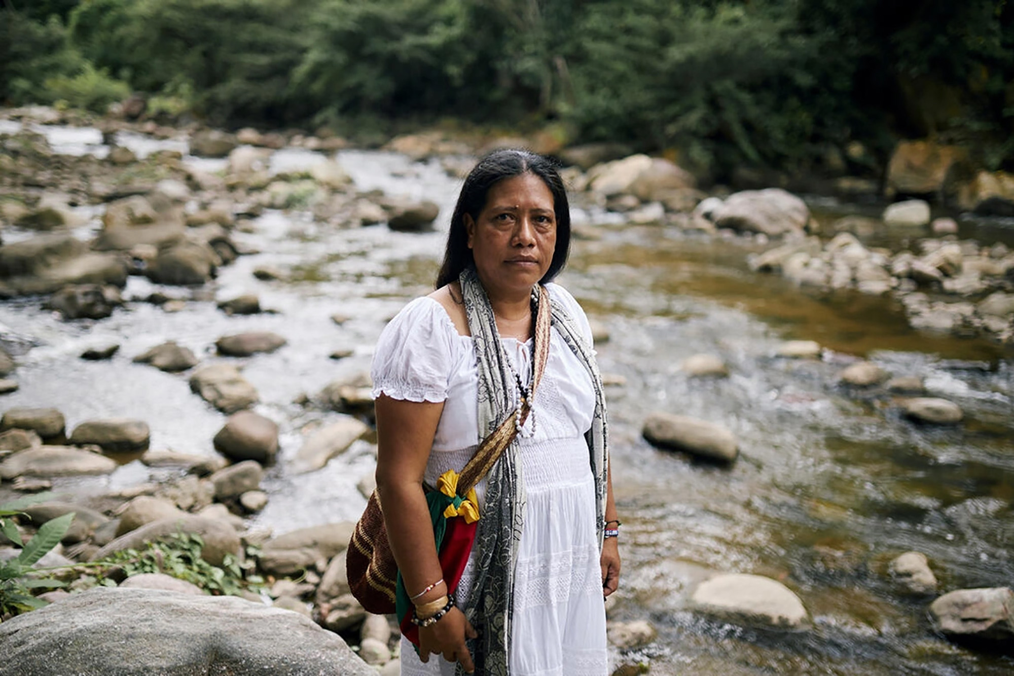 An indigenous woman standing with a river in the background.