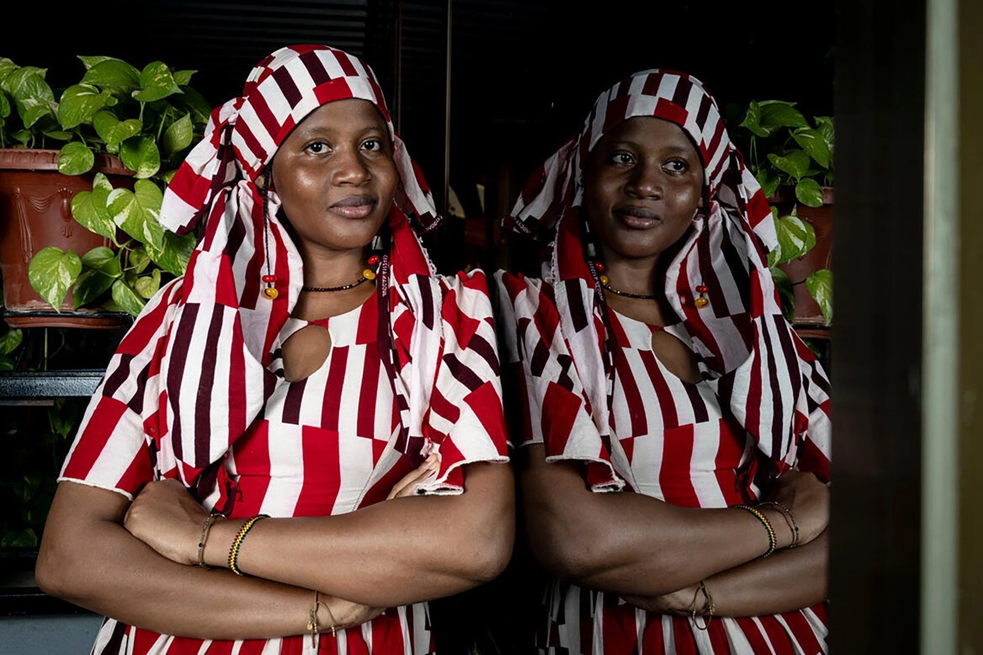 A woman from Burkina Faso poses for a photo with her body image reflected in a mirror.