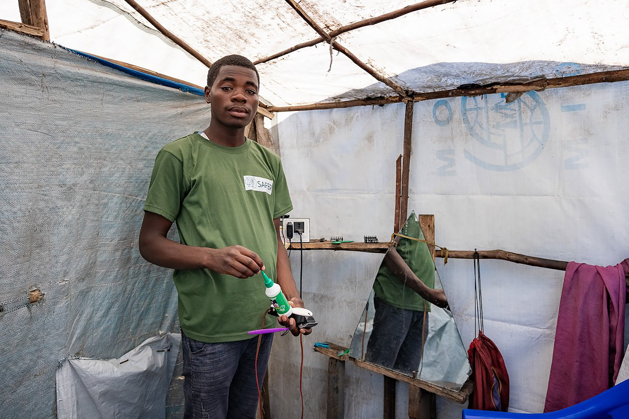 A barber from the Democratic Republic of the Congo in his makeshift barbershop in a displacement camp.