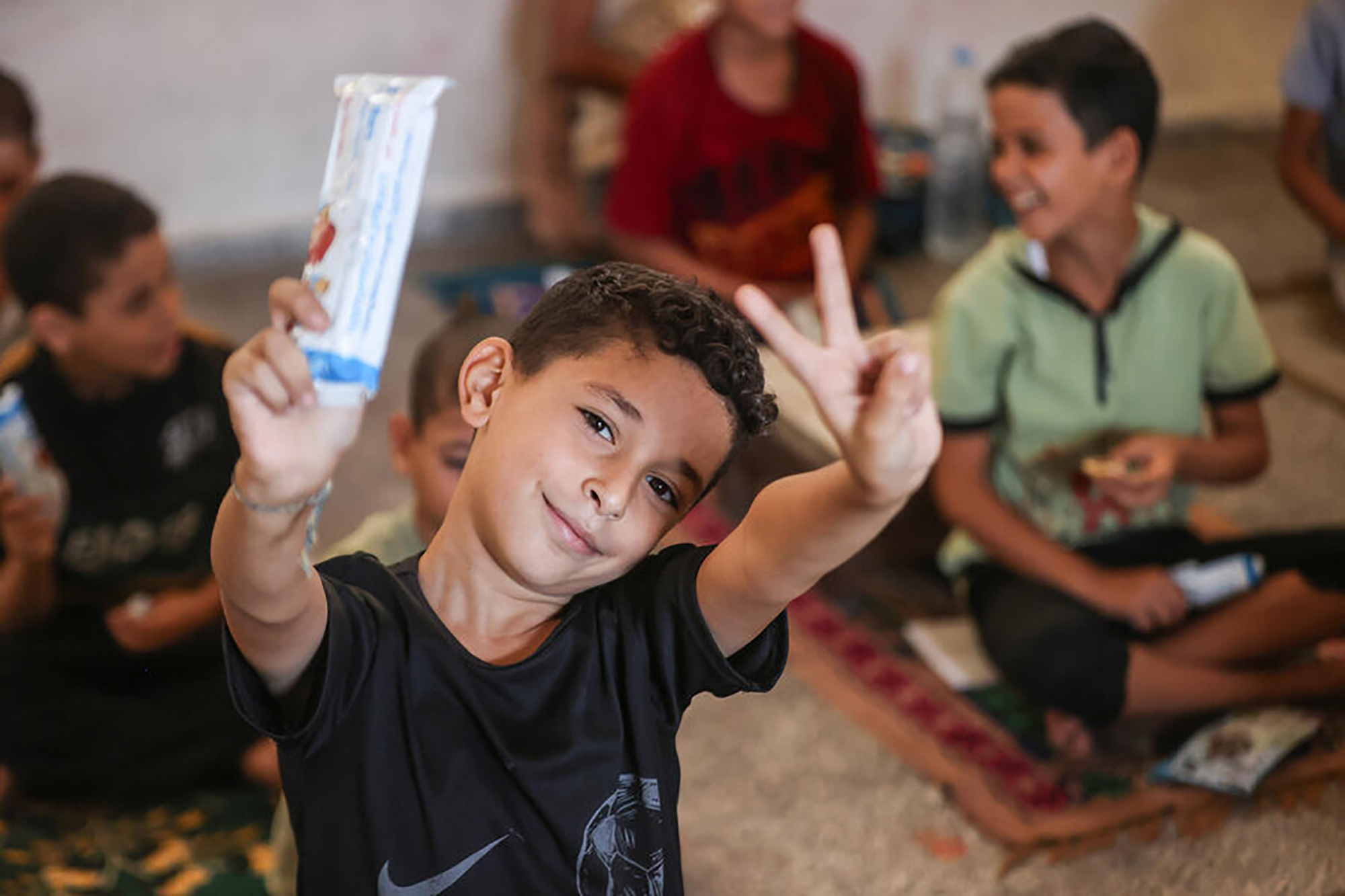 A child holds up a nutrition bar and shows the peace sign