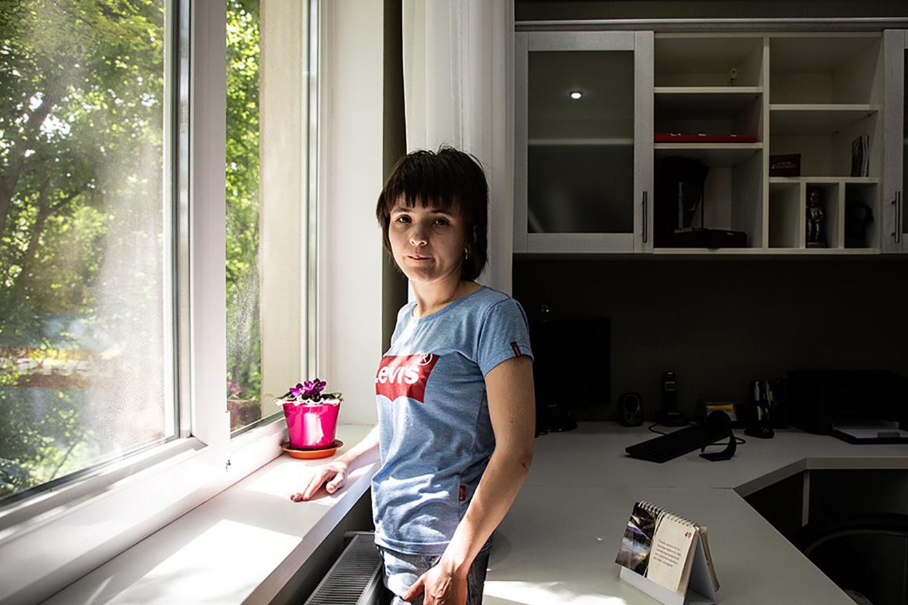 A woman standing before a window.