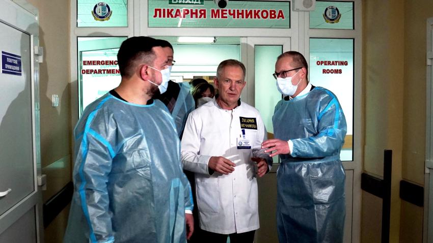 Hans with others wearing face masks are talking in a hall of a hospital.