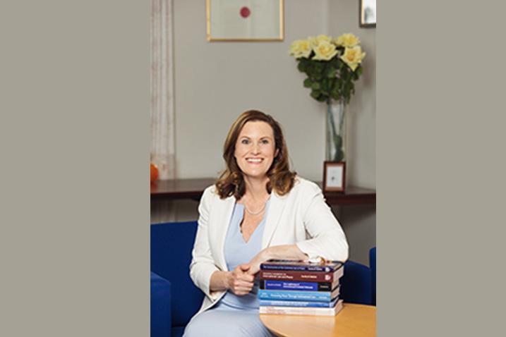 a lady sitting with her arm on a pile of books