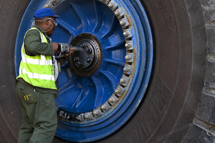 Haul truck being repaired and serviced by a worker.