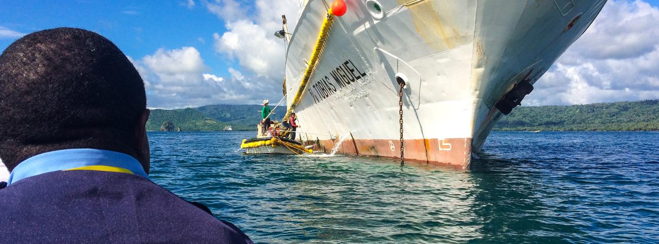 man on boat approaching ship