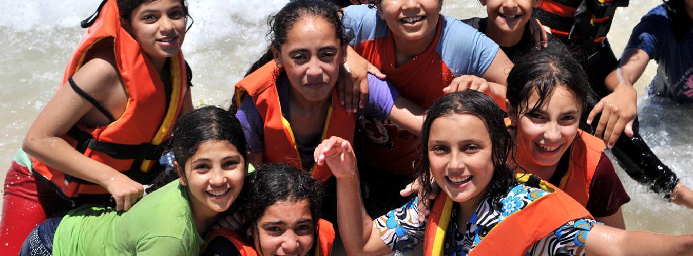 girls playing in the water at a beach with life jackets on