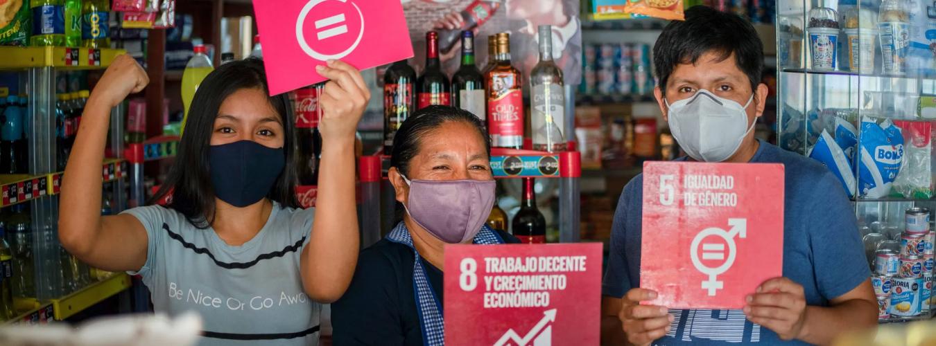family holding up SDG goals posters in small shop