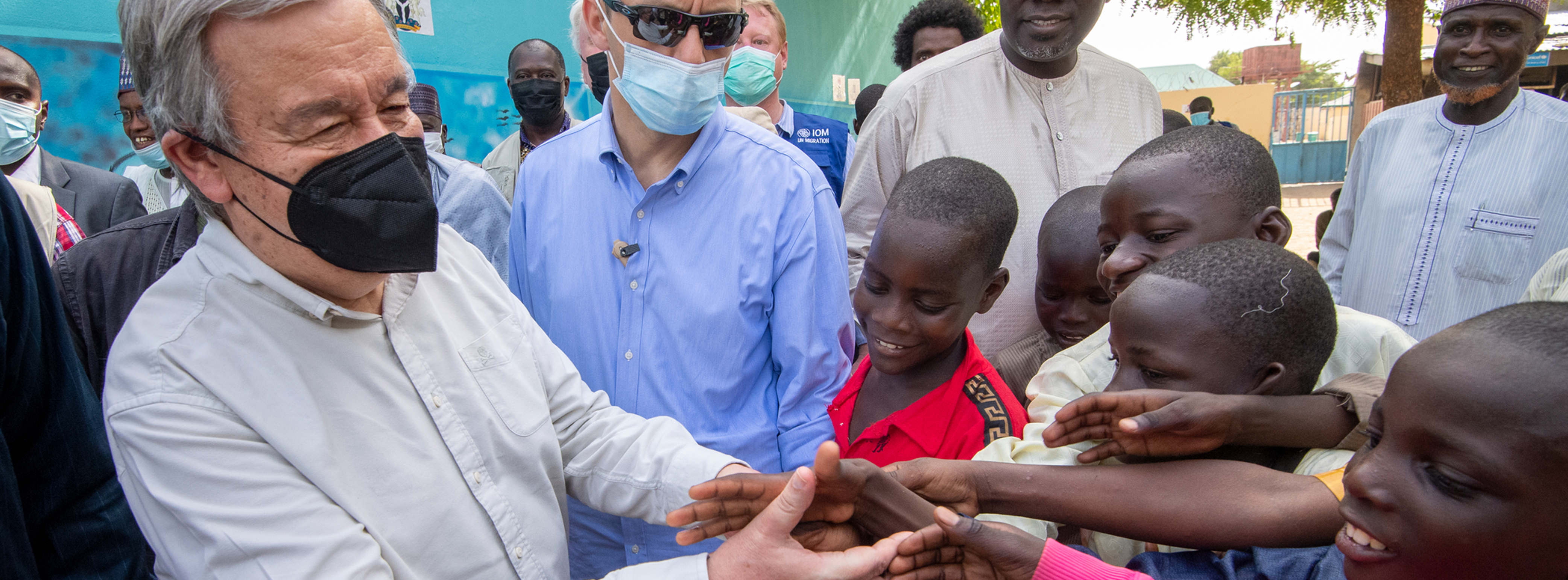 UN Secretary-General greets children while surrounded by people of all ages