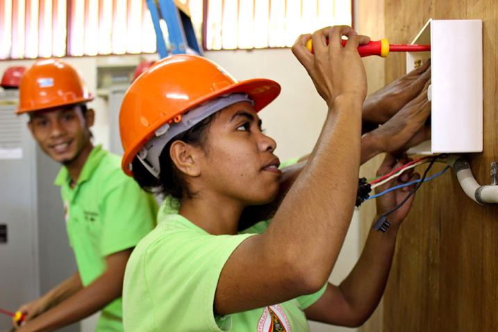 A woman wearing a hardhat works at a construction site. 