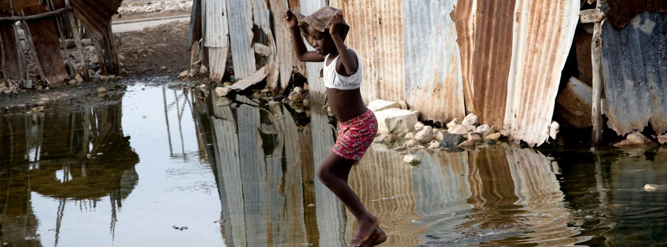 A Haitian girl crosses a flooded street in the aftermath of a hurricane.