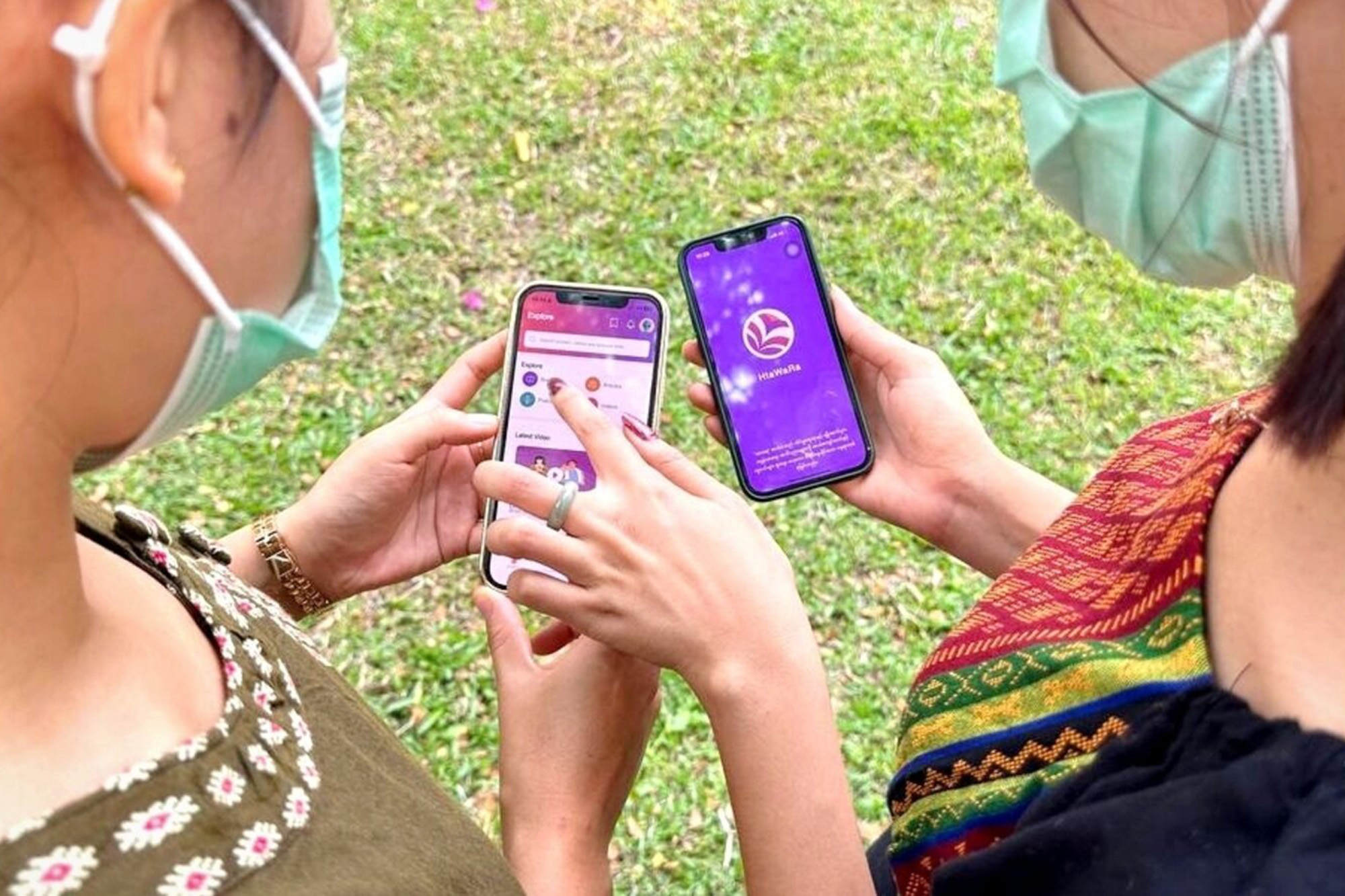 Two women look at the screen of their mobile phones as they use an app for sex education in Myanmar.