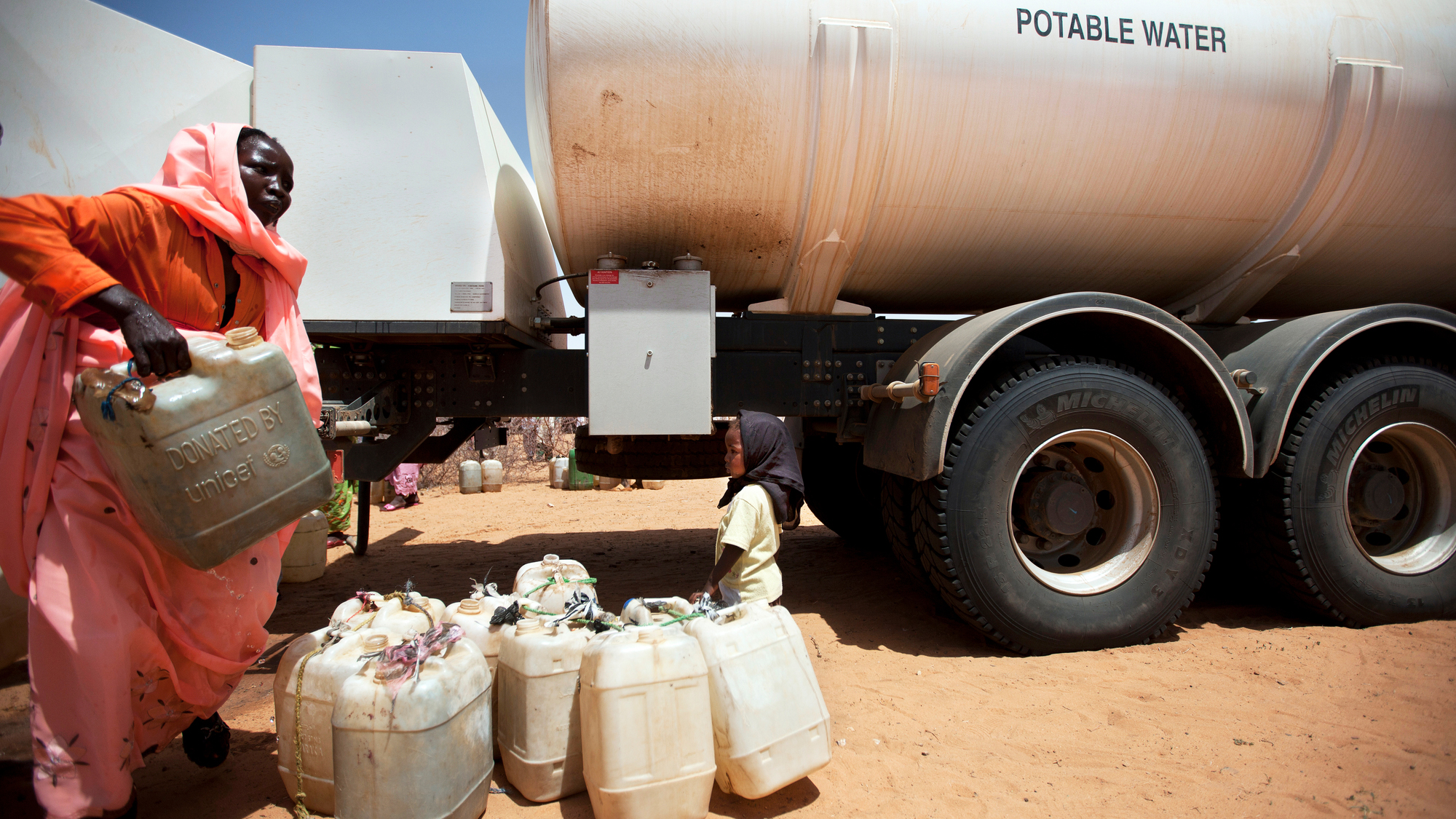 woman with child picking up potable water