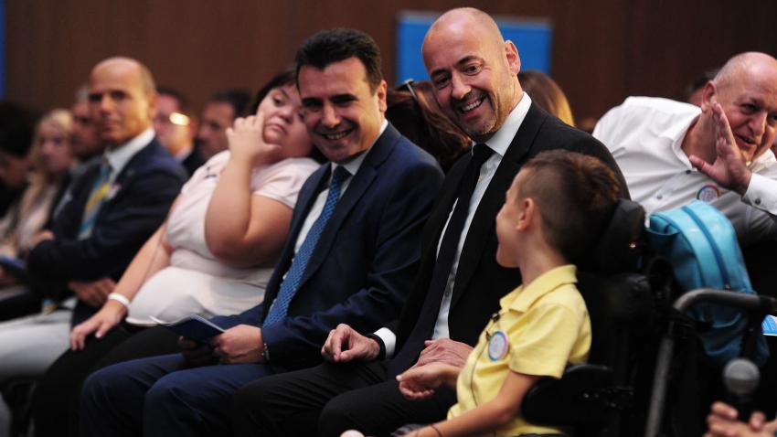Benjamin Perks and Prime Minister of North Macedonia sitting in audience with a child in a wheelchair