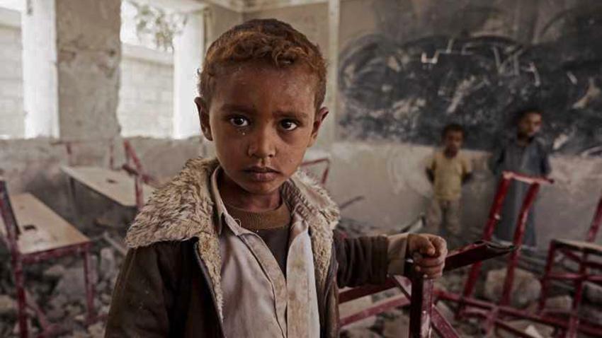 A child amid the ruins of war with two children in the background.