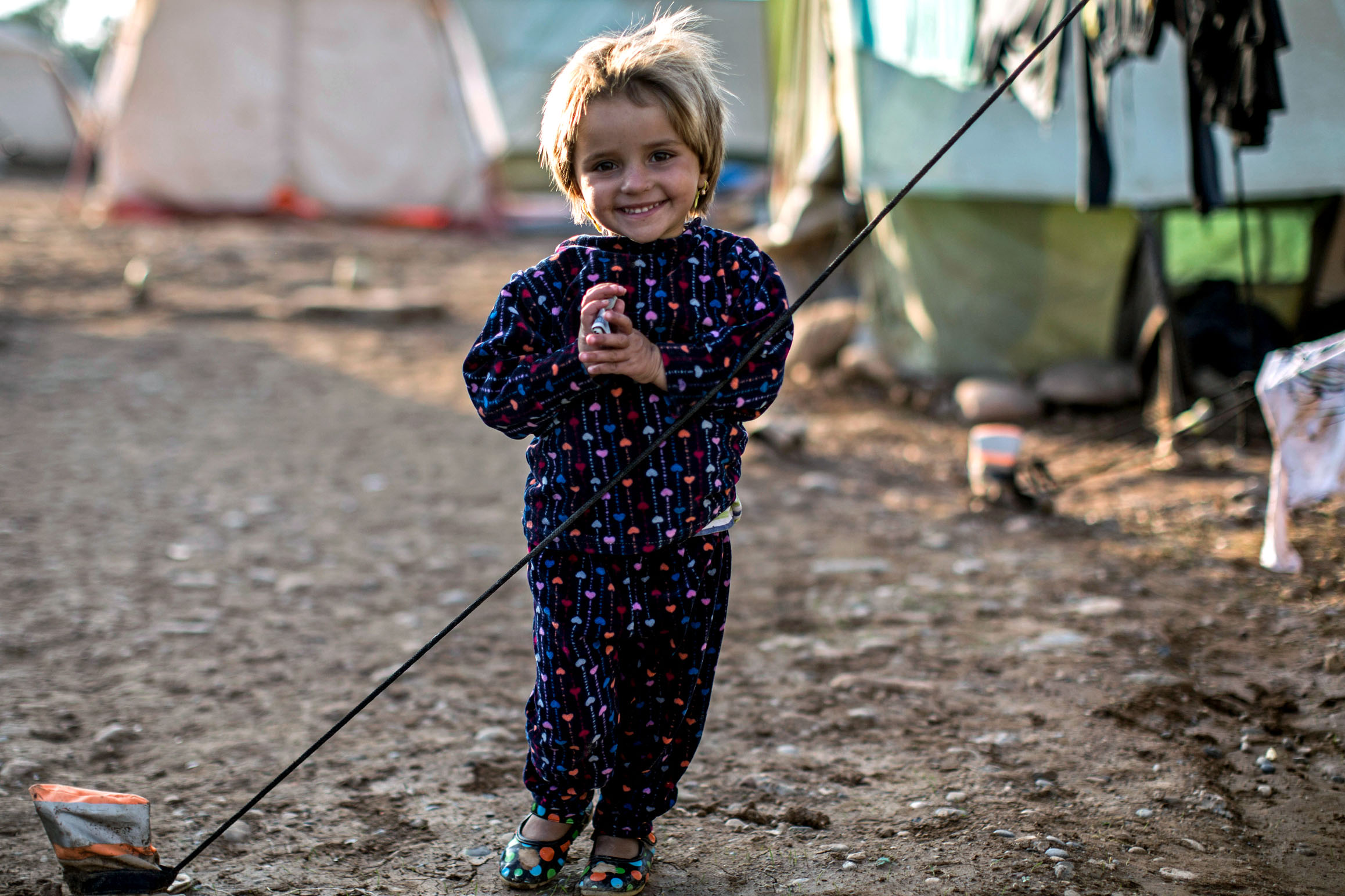 a young girl outside tent in a refugee camp