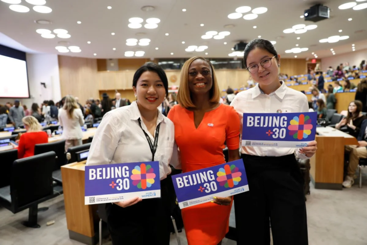 3 women grabbing a Beijing +30 poster in a UN Women's event